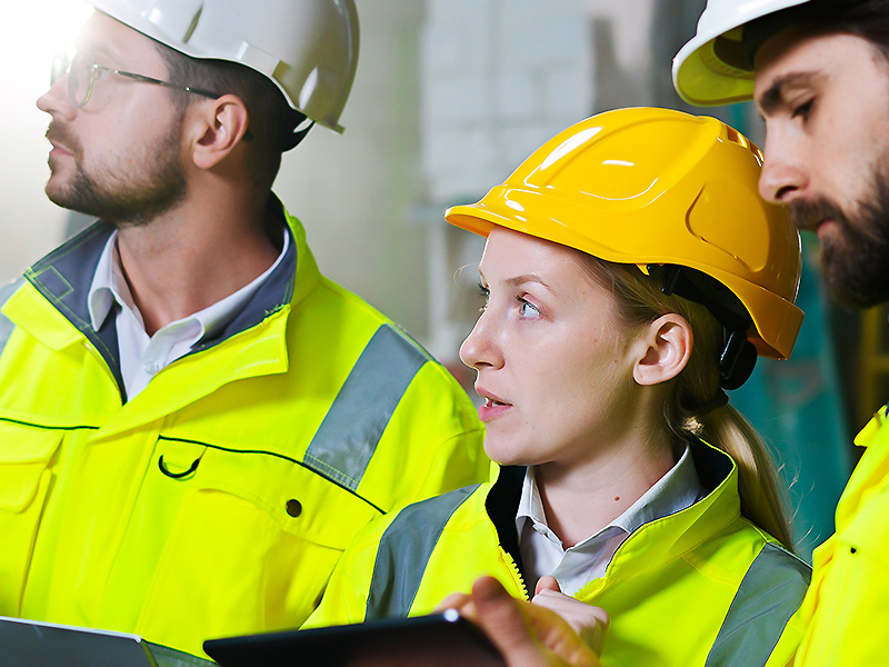 Three people in hard hats and high vis jackets